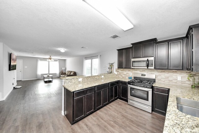 696 Rd 5105, Cleveland, TX 77327 - kitchen with stainless steel appliances, light wood-type flooring, open floor plan, a textured ceiling, and backsplash