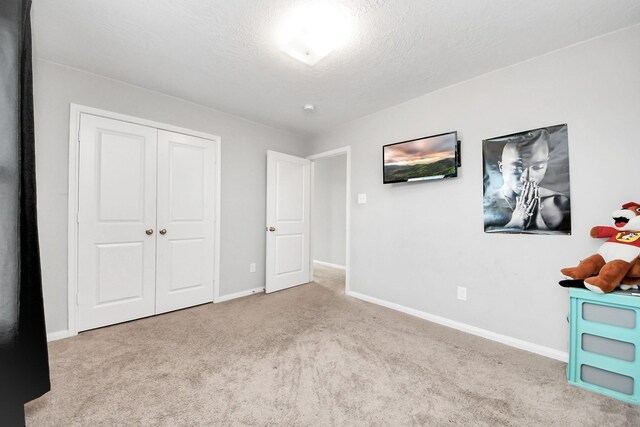 696 Rd 5105, Cleveland, TX 77327 - unfurnished bedroom with carpet, baseboards, a textured ceiling, and a closet