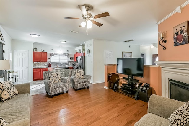 307 Squall Ct, Crosby, TX 77532 - living area with a ceiling fan, light wood-style floors, a glass covered fireplace, and baseboards
