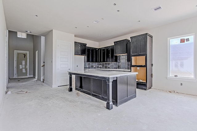 177 Peninsula Point Dr, Montgomery, TX 77356 - kitchen with dark cabinets, backsplash, a center island, and concrete floors