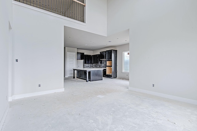 177 Peninsula Point Dr, Montgomery, TX 77356 - unfurnished living room featuring a high ceiling, concrete floors, and baseboards