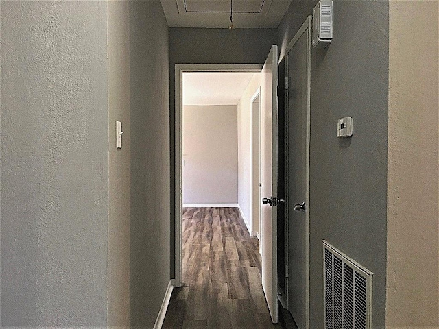 8322 Cabot St, Houston, TX 77078 - hall featuring a textured wall, dark wood-style flooring, baseboards, and attic access