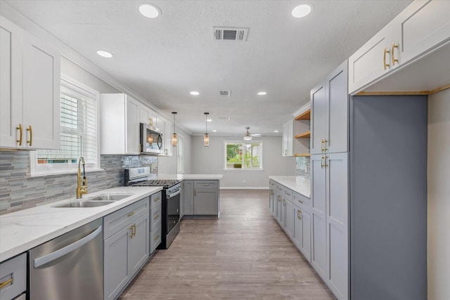 3518 Ball, Galveston, TX 77550 - kitchen featuring appliances with stainless steel finishes, a sink, gray cabinetry, light wood-style flooring, and tasteful backsplash