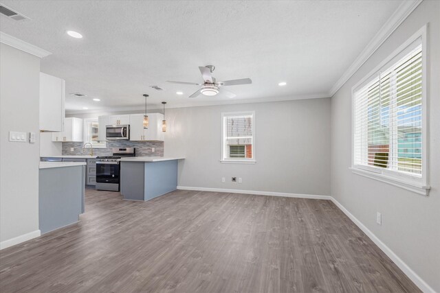 3518 Ball, Galveston, TX 77550 - kitchen with appliances with stainless steel finishes, healthy amount of natural light, wood finished floors, decorative backsplash, and ornamental molding