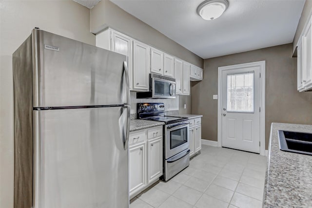 13060 Trail Hollow Dr Unit 3060, Houston, TX 77079 - kitchen with appliances with stainless steel finishes, white cabinets, light tile patterned floors, a sink, and baseboards