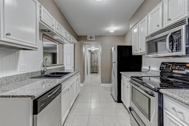13060 Trail Hollow Dr Unit 3060, Houston, TX 77079 - kitchen featuring appliances with stainless steel finishes, a sink, white cabinets, light tile patterned floors, and baseboards