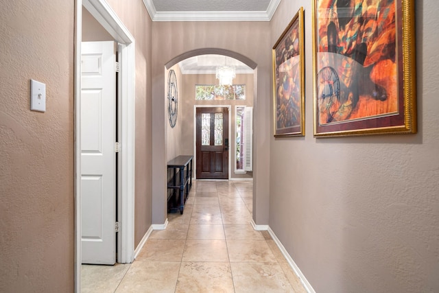 hallway featuring arched walkways, baseboards, a textured wall, light tile patterned floors, and crown molding
