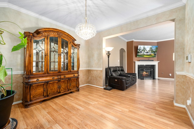 living area featuring wood finished floors, arched walkways, a chandelier, a premium fireplace, and ornamental molding