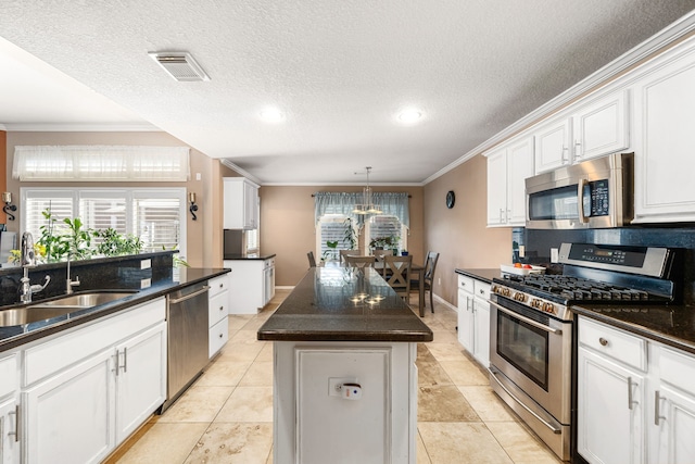 kitchen with stainless steel appliances, crown molding, a sink, dark countertops, and a center island