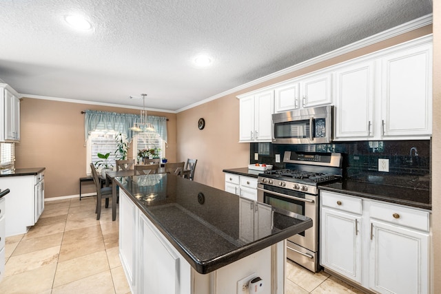 kitchen with appliances with stainless steel finishes, ornamental molding, backsplash, a center island, and white cabinetry