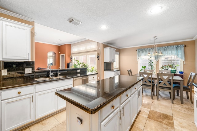 kitchen with a sink, stainless steel dishwasher, ornamental molding, white cabinets, and a textured ceiling