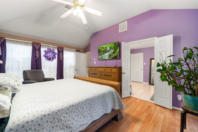 bedroom with lofted ceiling, light wood-style floors, a ceiling fan, and baseboards