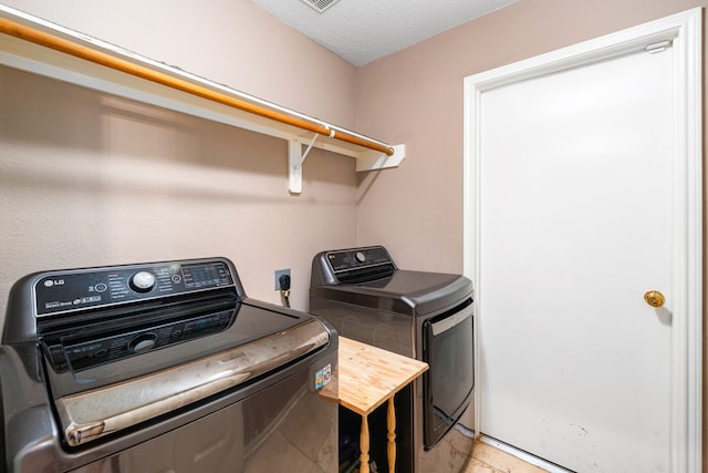 laundry room with washer and dryer and light tile patterned floors