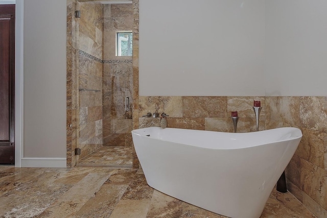 280 Sundog Rd, Huntsville, TX 77340 - bathroom featuring tile walls, a stall shower, a freestanding tub, and a wainscoted wall