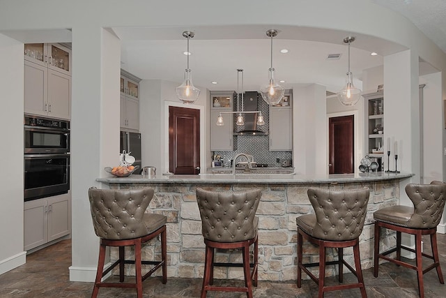 280 Sundog Rd, Huntsville, TX 77340 - kitchen featuring wall chimney exhaust hood, a kitchen breakfast bar, tasteful backsplash, a peninsula, and dark stone finish flooring