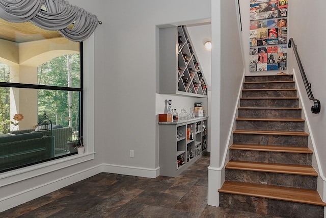 280 Sundog Rd, Huntsville, TX 77340 - stairs with stone finish floors, baseboards, and a bar