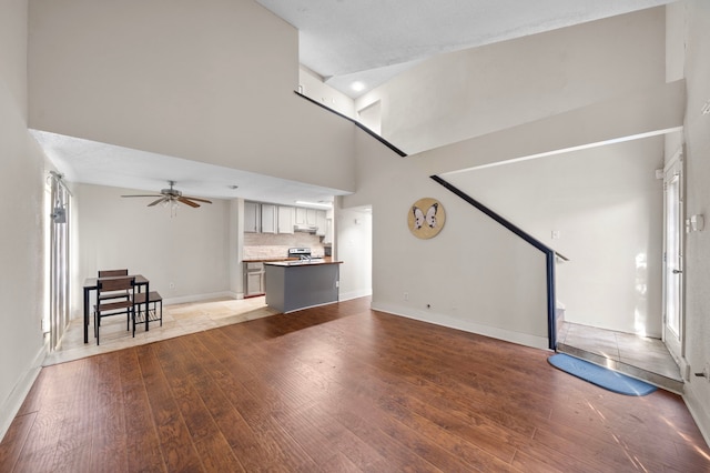 9537 Pagewood Ln Unit 9537, Houston, TX 77063 - unfurnished living room featuring hardwood / wood-style flooring, ceiling fan, a towering ceiling, and baseboards