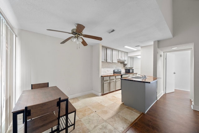 9537 Pagewood Ln Unit 9537, Houston, TX 77063 - kitchen featuring a sink, under cabinet range hood, a ceiling fan, tasteful backsplash, and a textured ceiling
