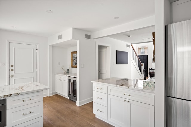 2421 Potomac Dr Unit C, Houston, TX 77057 - kitchen featuring freestanding refrigerator, beverage cooler, wood finished floors, light stone counters, and white cabinetry