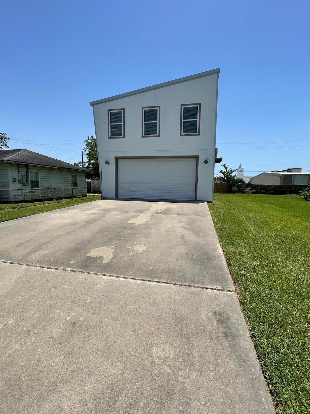 713 Lewis St, Clute, TX 77531 - view of front facade with a front lawn, driveway, an attached garage, and stucco siding