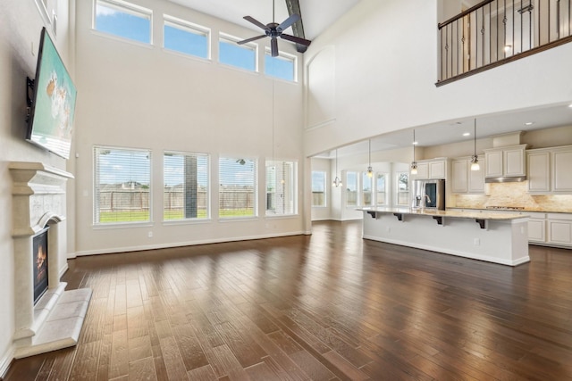 3115 Hillside Landing Trl, Katy, TX 77494 - unfurnished living room with ceiling fan, a towering ceiling, a glass covered fireplace, and plenty of natural light