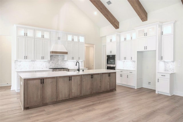 21332 Monarch Dr, Montgomery, TX 77316 - kitchen with premium range hood, a large island with sink, white cabinets, tasteful backsplash, and beam ceiling