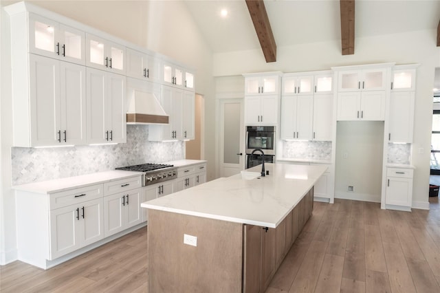21332 Monarch Dr, Montgomery, TX 77316 - kitchen with appliances with stainless steel finishes, custom range hood, light wood finished floors, decorative backsplash, and beam ceiling
