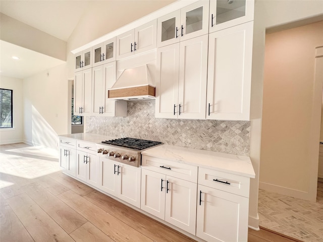 21332 Monarch Dr, Montgomery, TX 77316 - kitchen featuring stainless steel gas stovetop, custom exhaust hood, tasteful backsplash, white cabinets, and baseboards