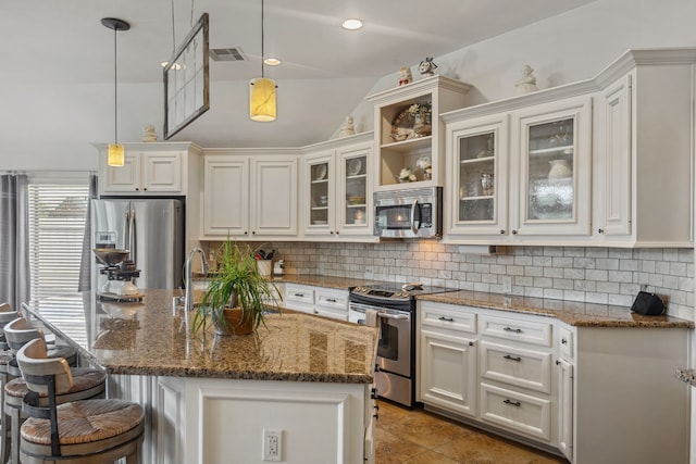2850 Woodland Glen Ln, Conroe, TX 77385 - kitchen with appliances with stainless steel finishes, vaulted ceiling, backsplash, white cabinetry, and a kitchen breakfast bar