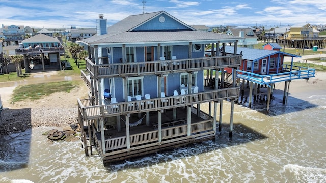 13134 Gulf Beach Dr, Freeport, TX 77541 - rear view of property featuring a shingled roof, boat lift, a chimney, and a wooden deck