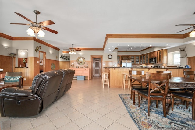 13134 Gulf Beach Dr, Freeport, TX 77541 - dining area with a ceiling fan, ornamental molding, a wainscoted wall, wooden walls, and light tile patterned floors