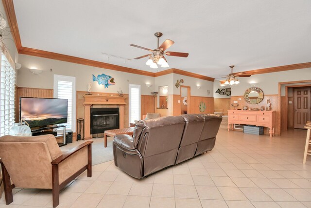 13134 Gulf Beach Dr, Freeport, TX 77541 - living room featuring a glass covered fireplace, a ceiling fan, crown molding, light tile patterned floors, and wooden walls
