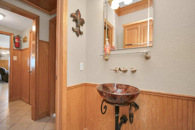 13134 Gulf Beach Dr, Freeport, TX 77541 - bathroom with wainscoting, wood walls, tile patterned flooring, and a sink