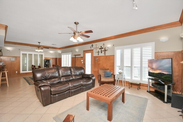13134 Gulf Beach Dr, Freeport, TX 77541 - living area featuring ceiling fan, wood walls, light tile patterned floors, ornamental molding, and wainscoting