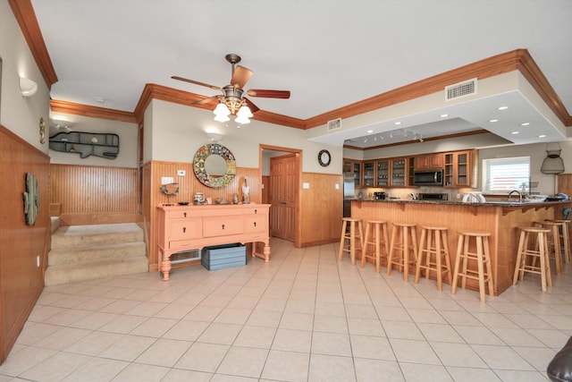 13134 Gulf Beach Dr, Freeport, TX 77541 - kitchen with stainless steel microwave, wainscoting, crown molding, a ceiling fan, and a kitchen breakfast bar