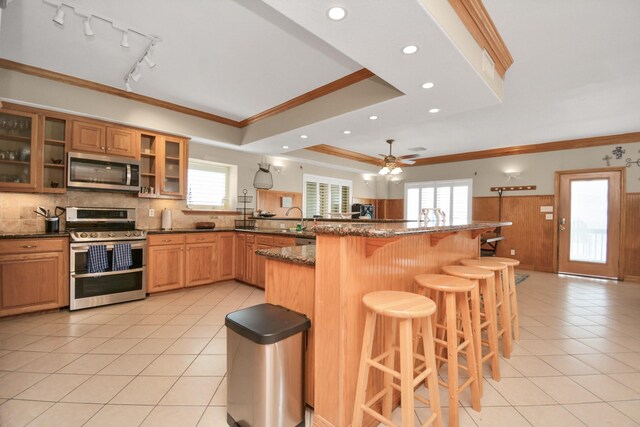 13134 Gulf Beach Dr, Freeport, TX 77541 - kitchen featuring stainless steel appliances, ornamental molding, light tile patterned floors, a breakfast bar area, and plenty of natural light