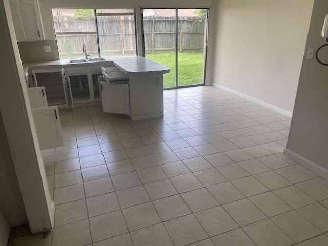 kitchen with tile countertops, light tile patterned floors, and healthy amount of natural light