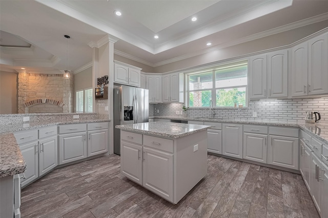 3331 Bridgette Ln, Baytown, TX 77523 - kitchen featuring a tray ceiling, stainless steel refrigerator with ice dispenser, decorative backsplash, crown molding, and white cabinetry