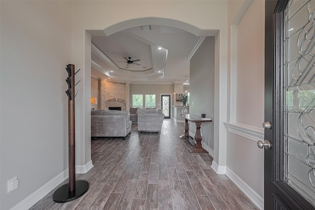 3331 Bridgette Ln, Baytown, TX 77523 - entryway featuring a ceiling fan, crown molding, a tray ceiling, dark wood finished floors, and a stone fireplace
