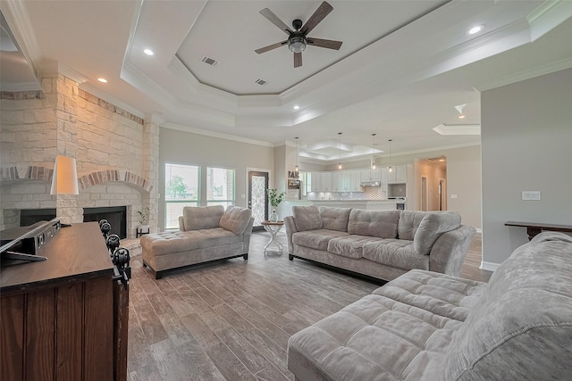 3331 Bridgette Ln, Baytown, TX 77523 - living area featuring a tray ceiling, a ceiling fan, crown molding, wood finished floors, and a fireplace