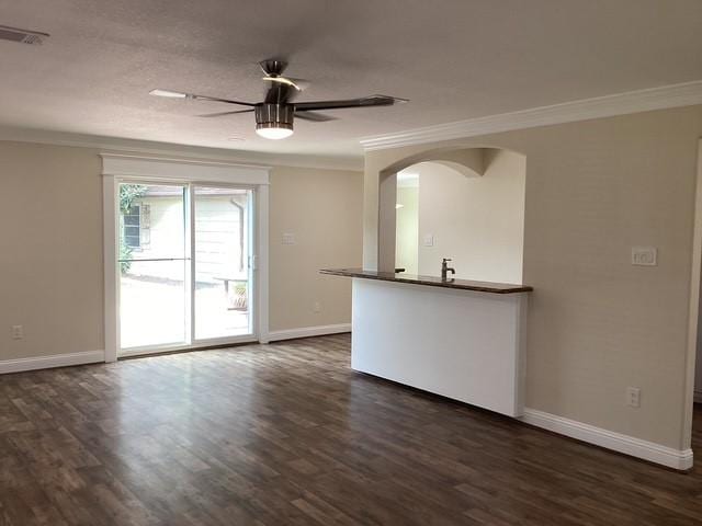 15311 Empanada Dr, Houston, TX 77083 - unfurnished living room featuring crown molding, arched walkways, baseboards, dark wood-style flooring, and a ceiling fan