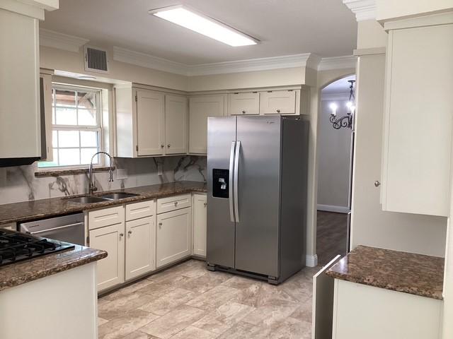 15311 Empanada Dr, Houston, TX 77083 - kitchen featuring stainless steel appliances, a sink, dark stone counters, ornamental molding, and decorative backsplash