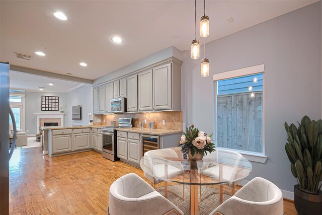 814 Nicholson St, Houston, TX 77007 - kitchen with appliances with stainless steel finishes, beverage cooler, a peninsula, backsplash, and light wood finished floors