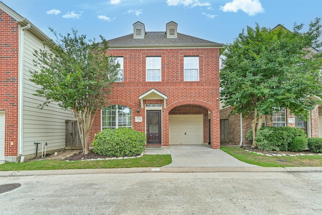 georgian-style home featuring brick siding, driveway, a garage, and roof with shingles