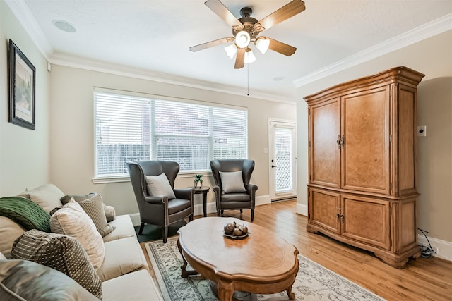 living room featuring light wood finished floors, ceiling fan, ornamental molding, and baseboards
