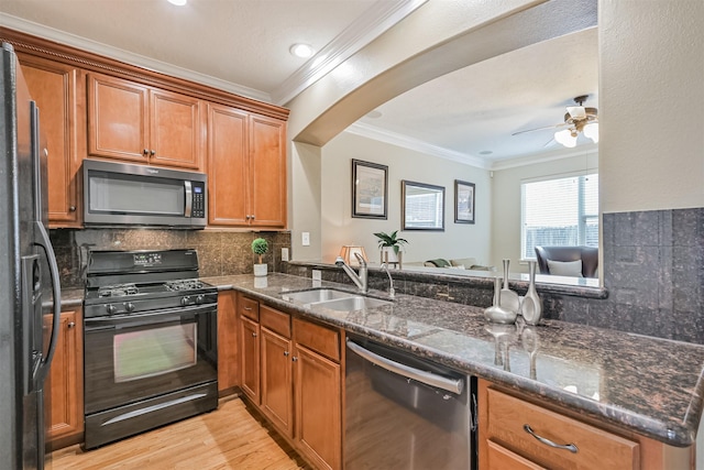 kitchen with black appliances, a sink, ornamental molding, tasteful backsplash, and brown cabinetry