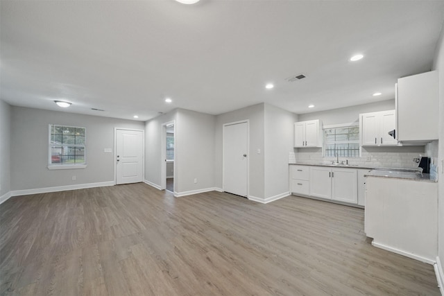 5313 Doolittle Blvd, Houston, TX 77033 - kitchen featuring baseboards, light wood-style floors, white cabinetry, open floor plan, and light countertops