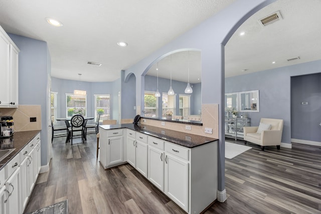 kitchen with dark wood-style flooring, arched walkways, white cabinetry, and recessed lighting