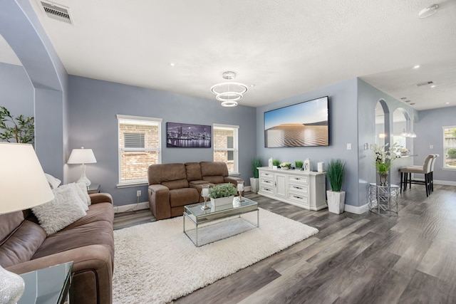 living area with arched walkways, baseboards, wood finished floors, and recessed lighting