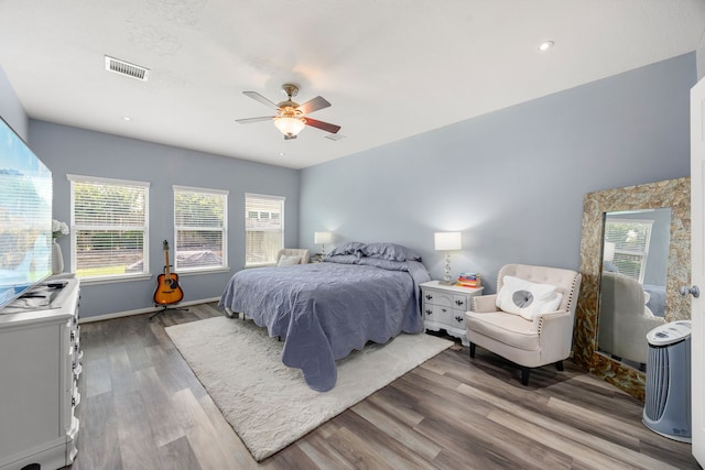 bedroom featuring wood finished floors, multiple windows, ceiling fan, baseboards, and recessed lighting